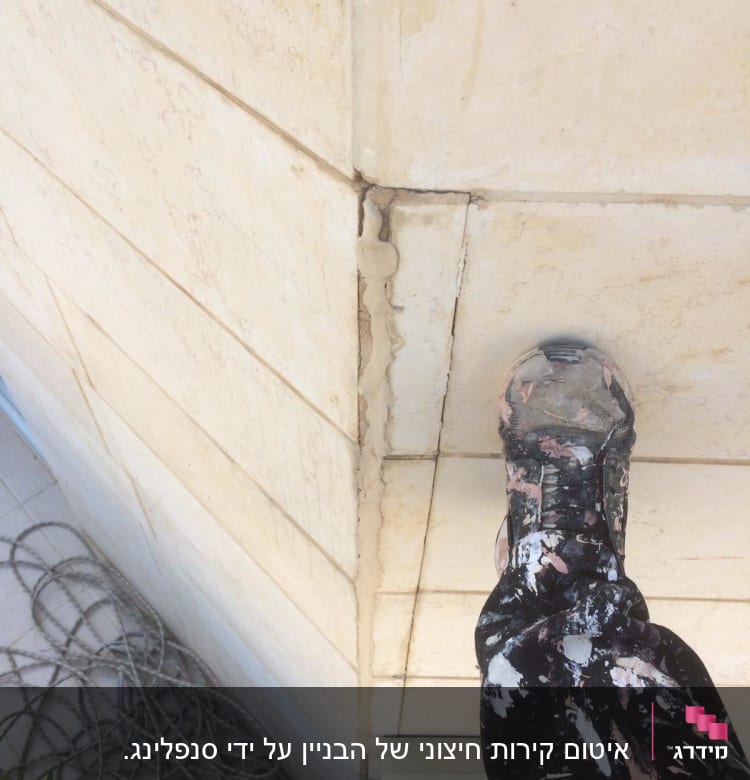 אדם עומד על קיר עם סדק ותיקון איטום